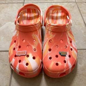A pair of brand new Crocs with two Jibbitz included.